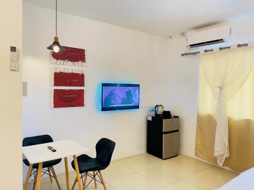 um quarto com uma mesa e cadeiras e uma televisão na parede em R Block Commercial Building em Naga
