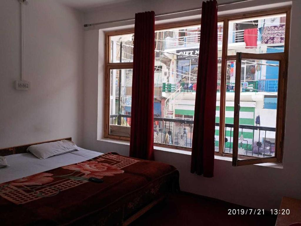 a bedroom with a bed and two windows at OYO Holidayinn in Kargil
