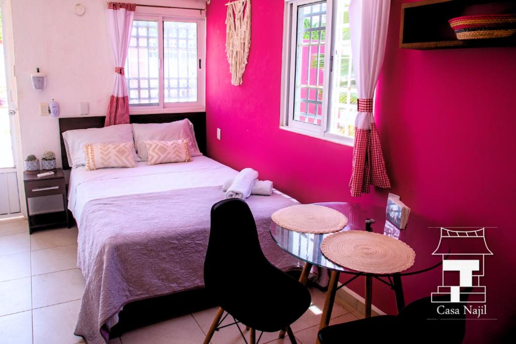 Schlafzimmer mit rosa Wänden, einem Bett und einem Tisch in der Unterkunft Najil House St1 in Bacalar