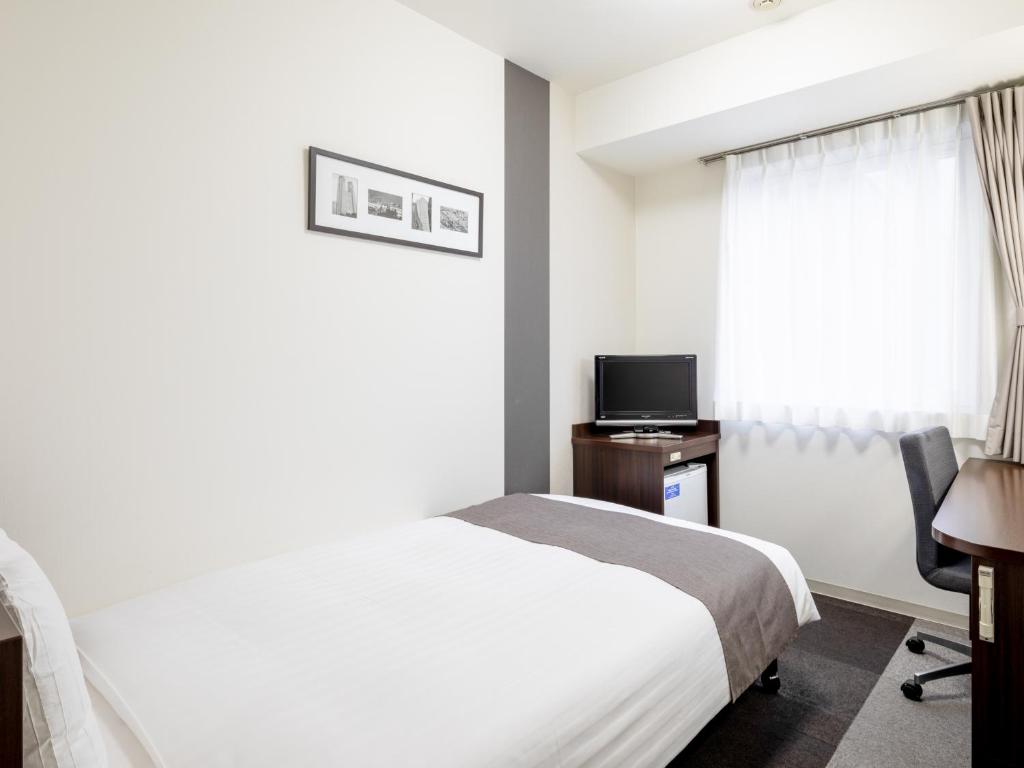 a bedroom with a bed and a desk and a television at Comfort Hotel Tokyo Kanda in Tokyo