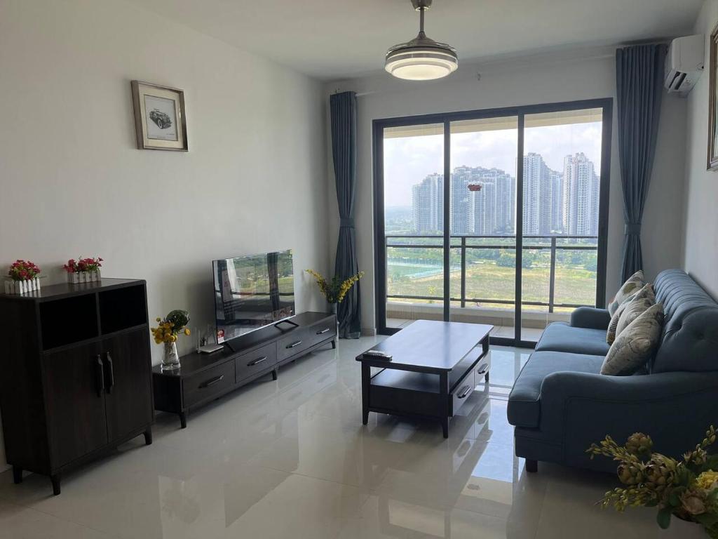 un salon avec un canapé bleu et une grande fenêtre dans l'établissement Forest city Ataraxia park homestay, à Johor Bahru