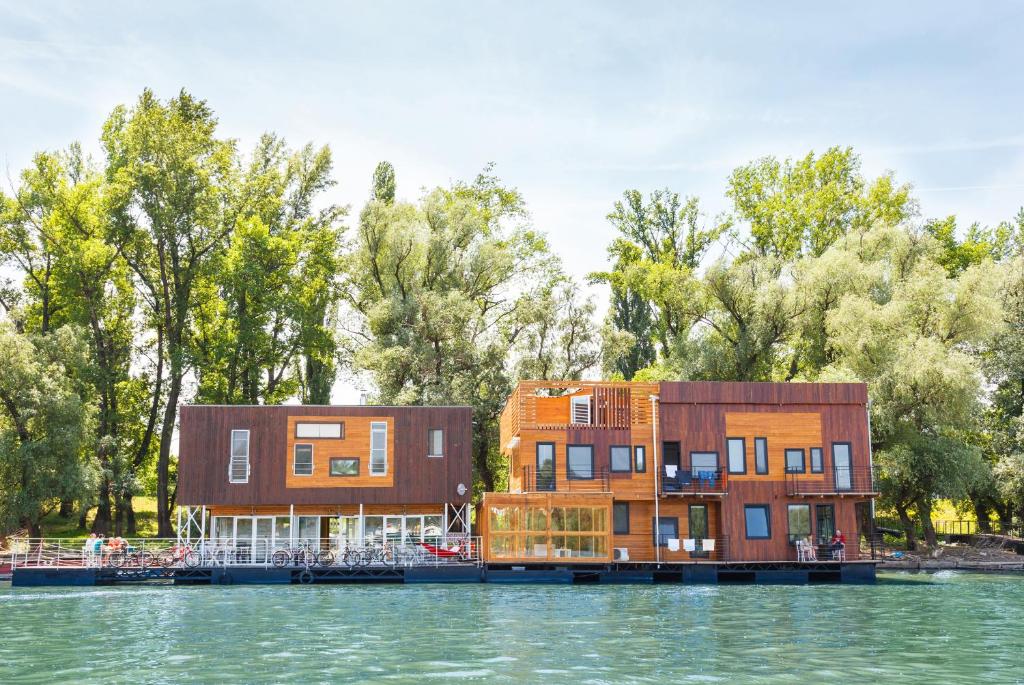 two buildings on the water next to a lake at ArkaBarka Floating Hostel in Belgrade