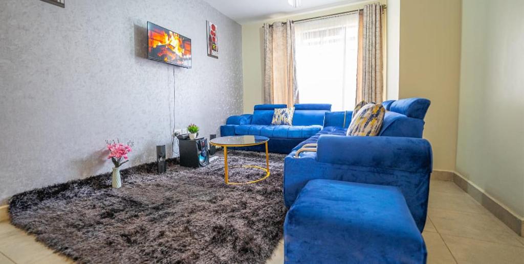 salon z niebieskimi kanapami i dywanem w obiekcie Lux Suites Cavendish Square Apartments w mieście Syokimau