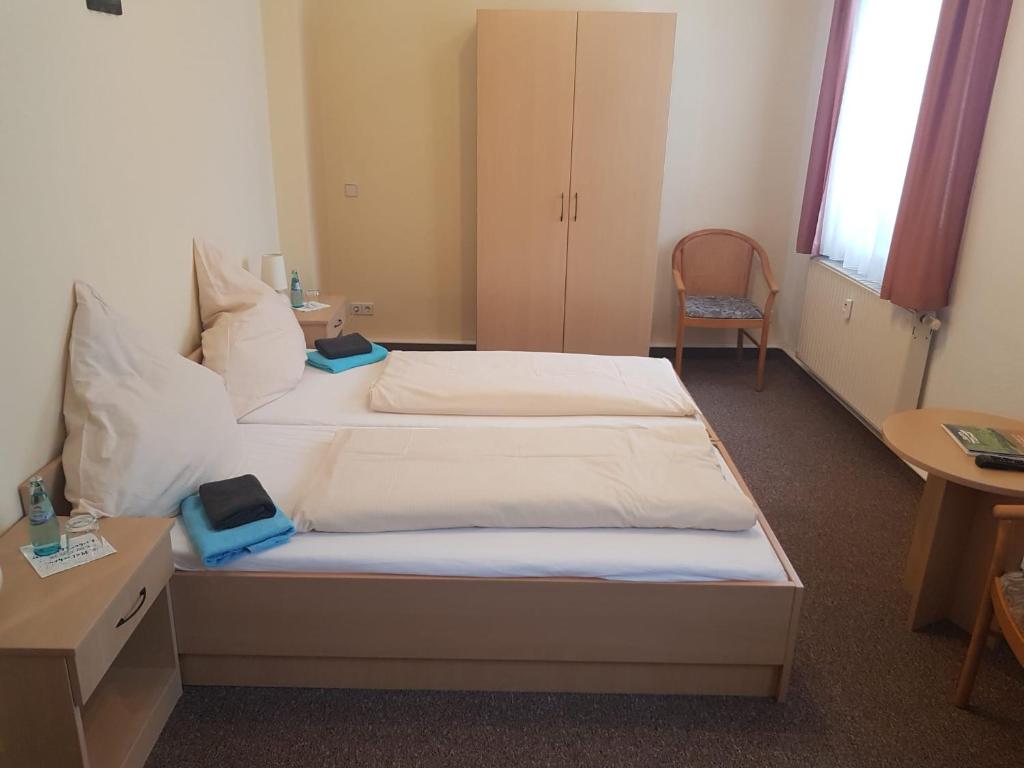 a hotel room with two beds and a desk at Pension "Zur Katze" in Gelenau