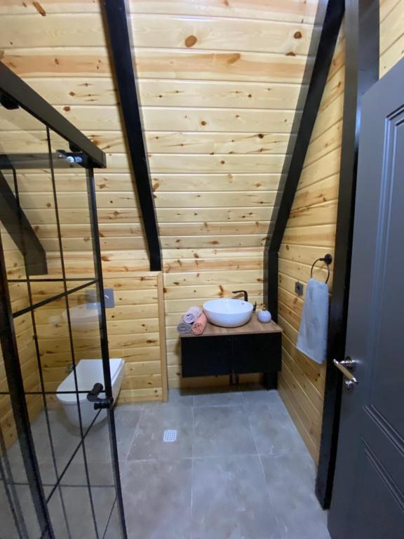 ein Badezimmer mit einer Holzwand mit einer Badewanne und einem Waschbecken in der Unterkunft Gohali Bungalov in Trabzon