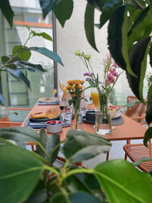Hotel Maison Brunon, a table with plates of food and flowers in vases at Maison Brunon in Bruges