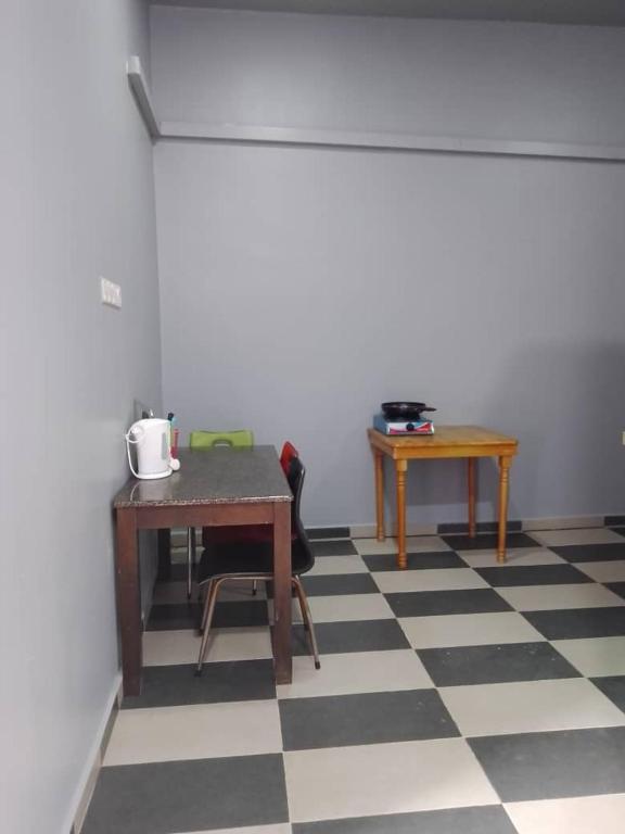 Cette chambre dispose d'un sol en damier avec une table et une table. dans l'établissement Z homestay, à Permatang Pauh