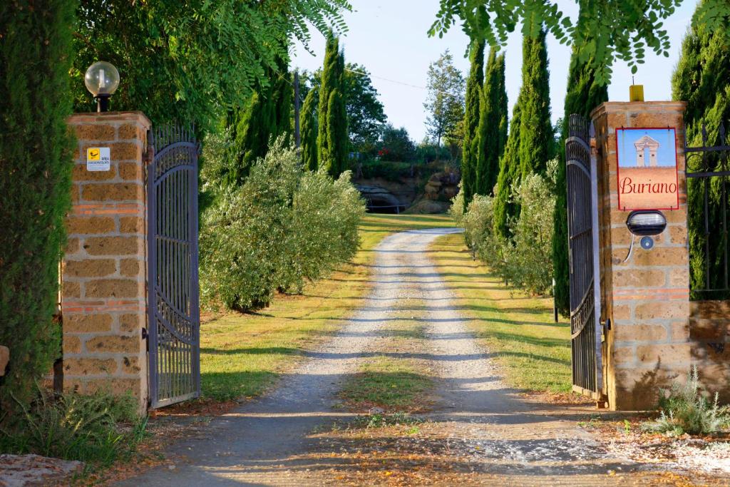 a gate to a driveway with trees and a road at Agriturismo Buriano in Lubriano
