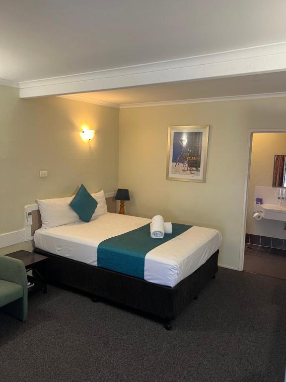 um quarto de hotel com uma cama e uma cadeira em Biloela Centre Motel & Steakhouse Restaurant em Biloela