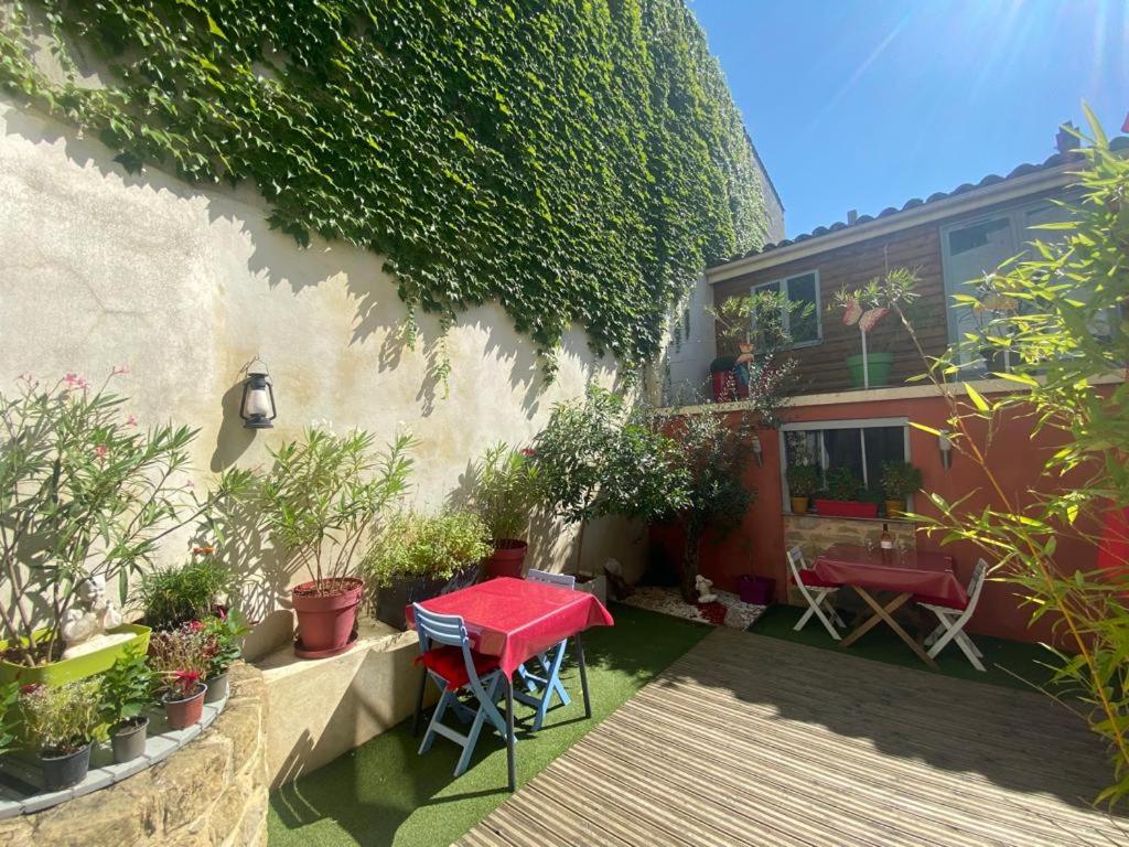 a patio with a red table and chairs in front of a building at Chambre privée au calme excellente prestation in Castelnaudary