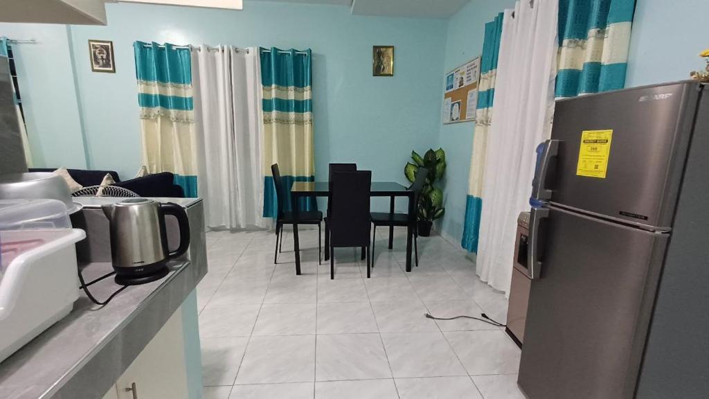 uma cozinha com um frigorífico e uma mesa com cadeiras em Jens Samal Vacation Rental - Centrally Located - Fully Furnished 2br WIFI em Babak