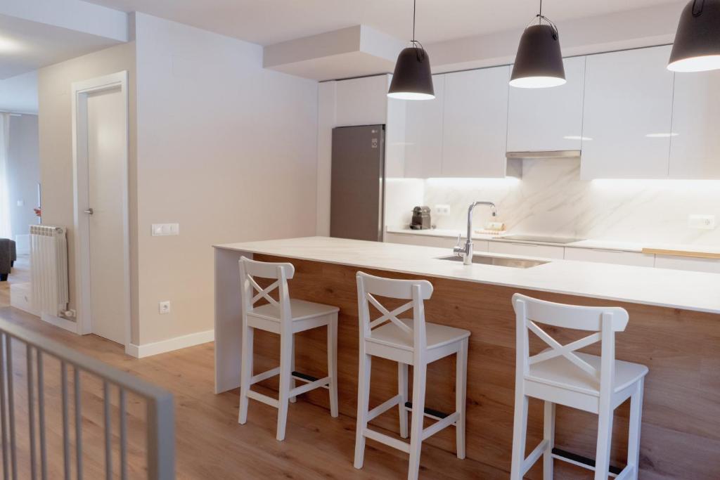 eine Küche mit weißen Arbeitsflächen und weißen Stühlen in der Unterkunft LA CASA del TOMÀS in Pobla de Segur