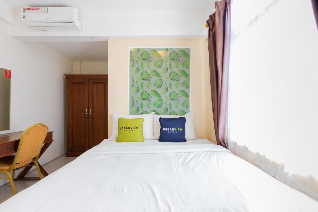 a bedroom with a white bed with two pillows at Urbanview Erga Family Residence Syariah Surabaya in Surabaya