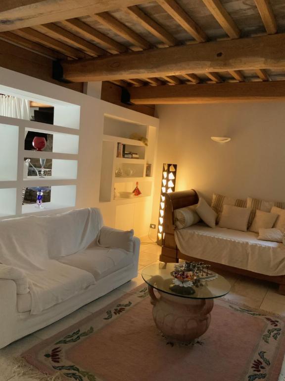 uma sala de estar com dois sofás brancos e uma mesa em La casa dei caprioli appartamento in casale em Montepulciano