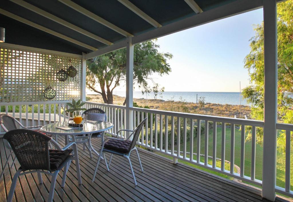 een veranda met een tafel en stoelen en de oceaan bij Out of the Blue - Busselton in Busselton