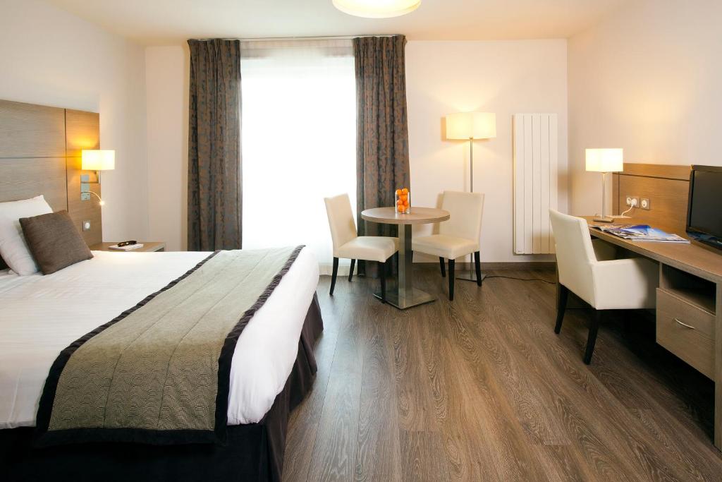 a hotel room with a bed and a desk and a table at Residhome du Théâtre in Valenciennes