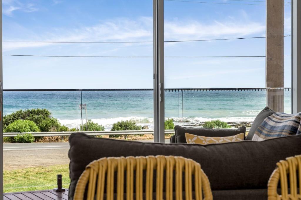 a living room with a couch and a view of the ocean at Six Degrees - beach across the road in Wye River
