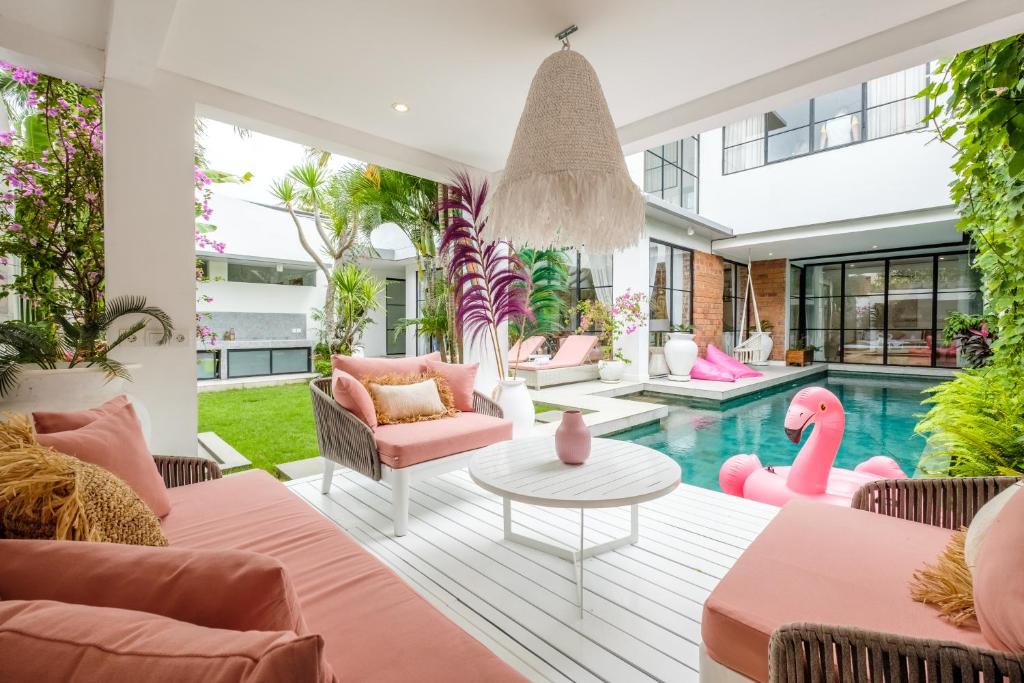 a living room with pink furniture and a swimming pool at Maison Jolie Villa by Hombali in Canggu