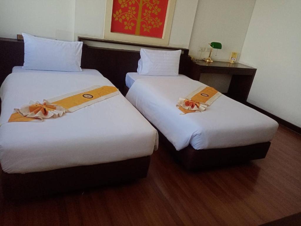 Grand Phranakhon Hotel في فرا ناخون سي أيوتثايا: سريرين في غرفة الفندق ذات شراشف بيضاء