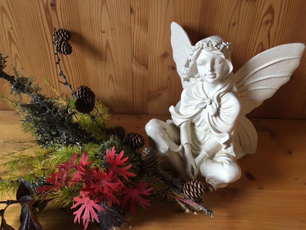 una estatua de ángel blanco sentada junto a un arreglo floral en La Demeure des Elfes, en Albinen