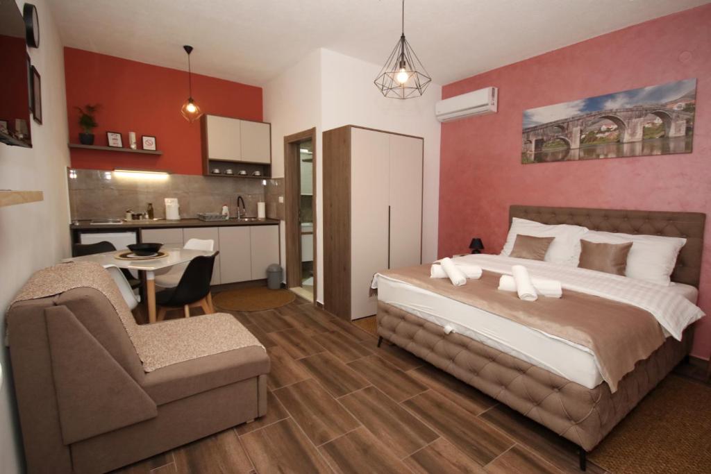 een slaapkamer met een bed en een bank en een keuken bij P&P Apartmans Drapić in Trebinje
