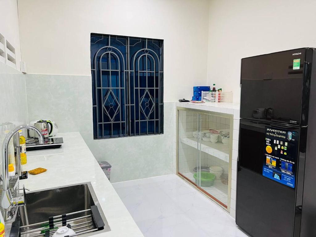 a kitchen with a sink and a black refrigerator at Charis Home- Tay Ninh in Tây Ninh