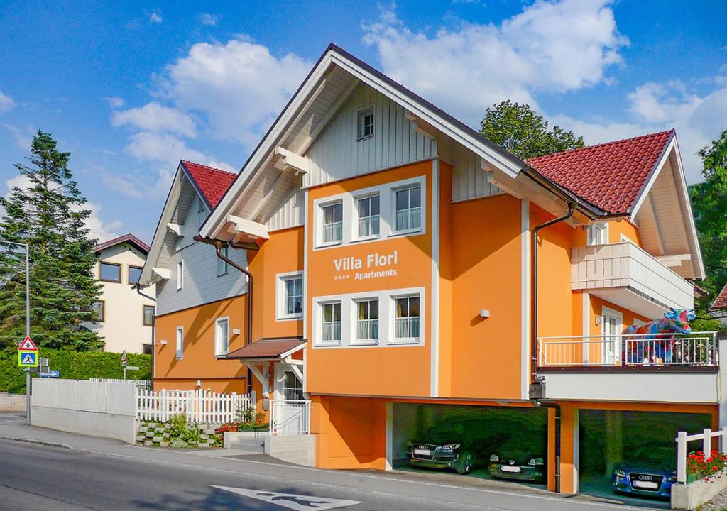 un bâtiment jaune et orange avec une clôture blanche dans l'établissement Villa Florl, à Schladming