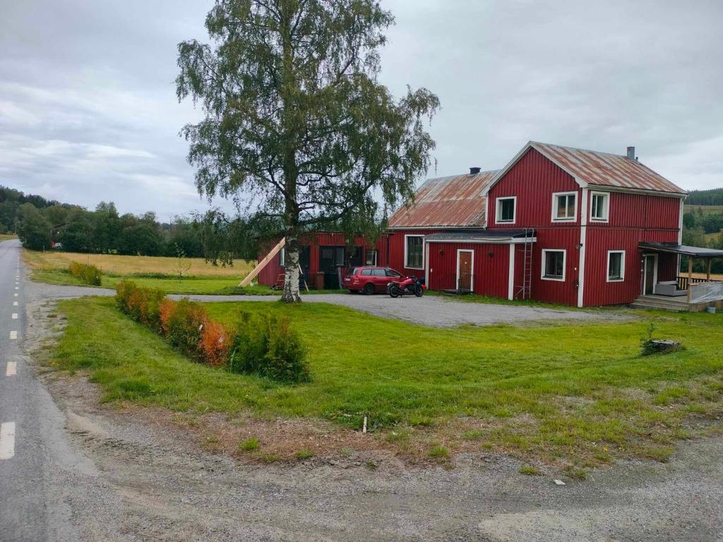 um celeiro vermelho sentado ao lado de uma estrada em Vackert naturnära i Höga Kusten 