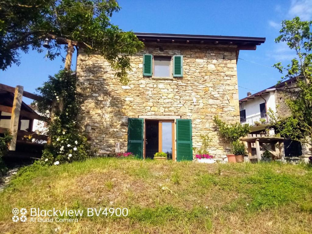 una antigua casa de piedra con persianas verdes en Segarati Relax La Maiolica, en Bardi