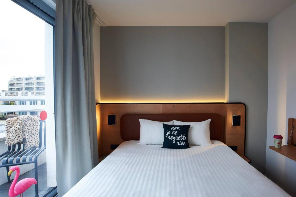 a bedroom with a bed and a large window at Moxy Paris Bastille in Paris