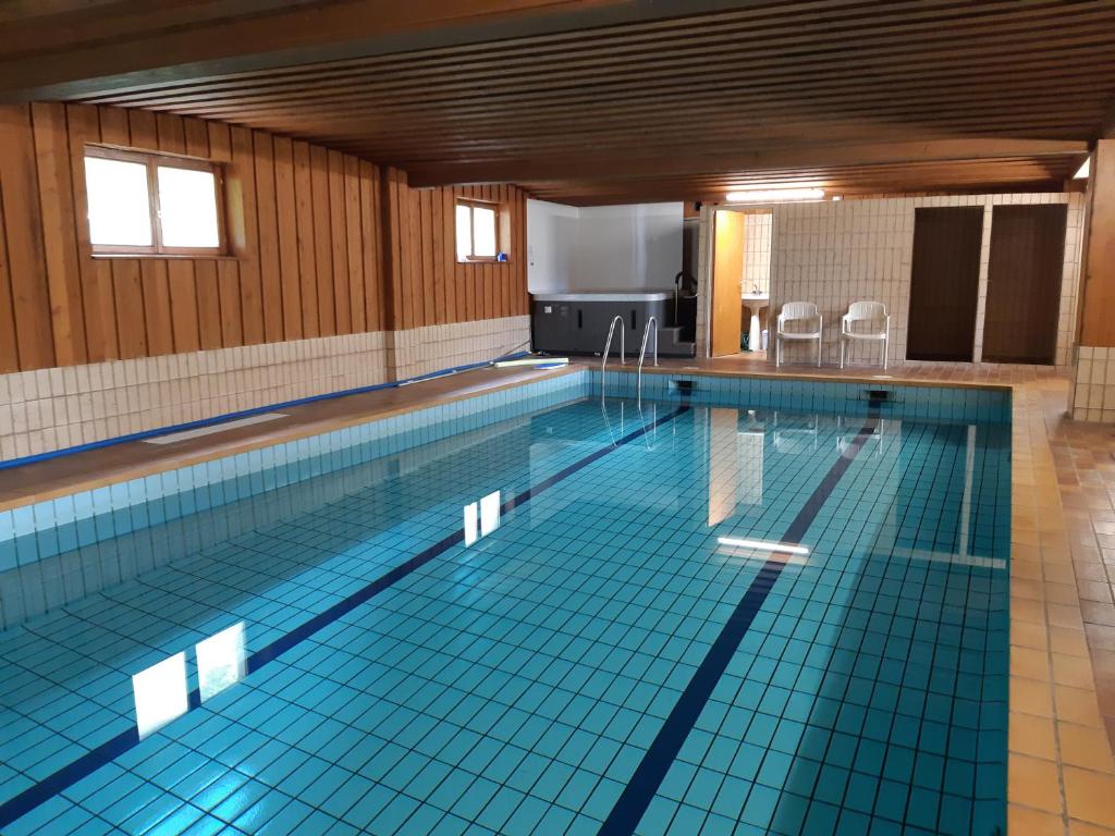 - une grande piscine revêtue de carrelage bleu dans l'établissement Hotel-Spa & Restaurant Logis Domaine Langmatt, à Murbach