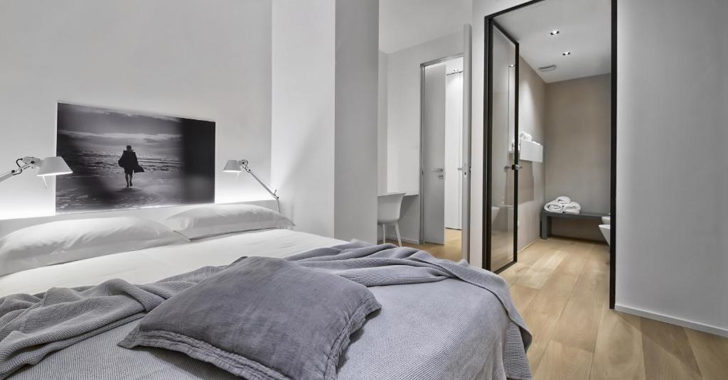 ein weißes Schlafzimmer mit einem Bett und einem Spiegel in der Unterkunft Luxury Suites Collection - SHANTUNG Double Room in Riccione