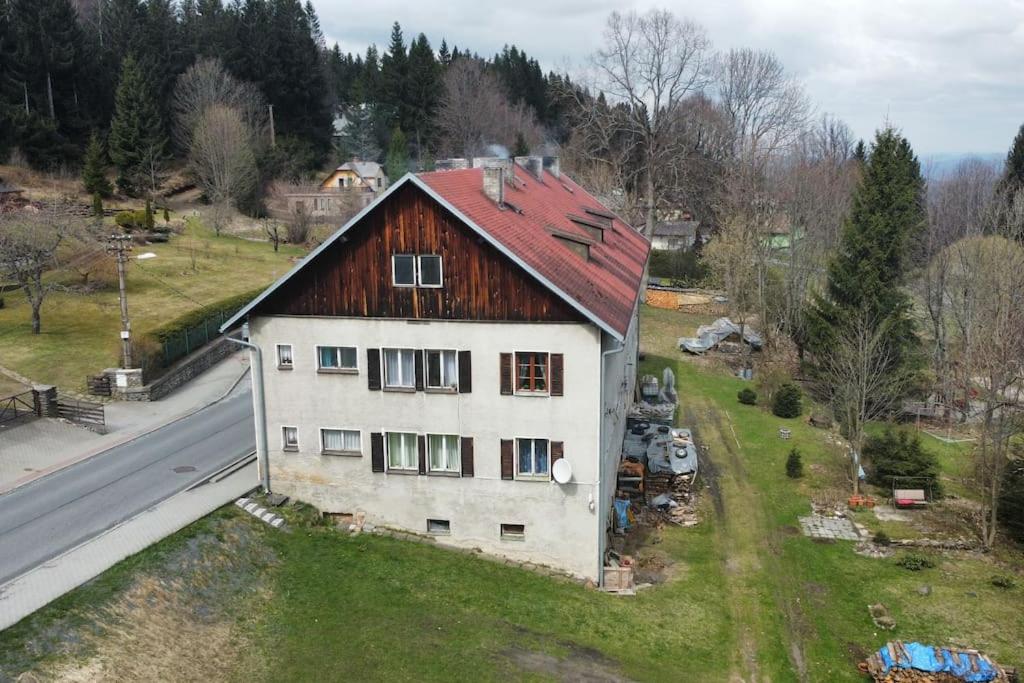 una casa blanca con techo rojo al lado de una carretera en Pronájem bytu 3+kk, en Železná Ruda