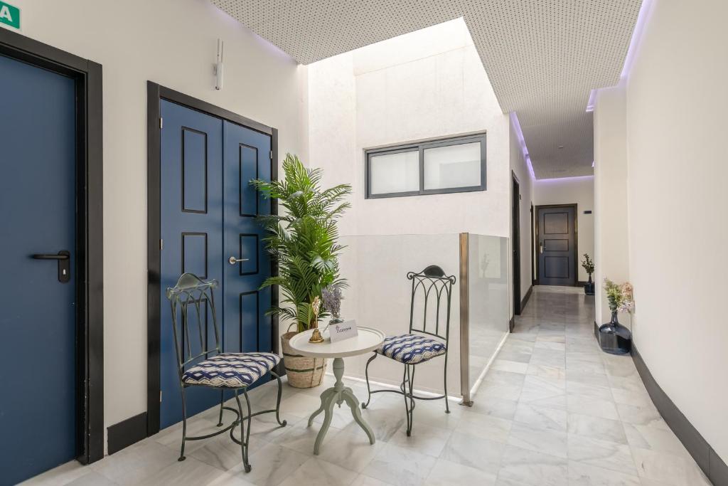 um corredor com uma mesa e cadeiras e uma porta azul em Cicerone de Sevilla em Sevilha