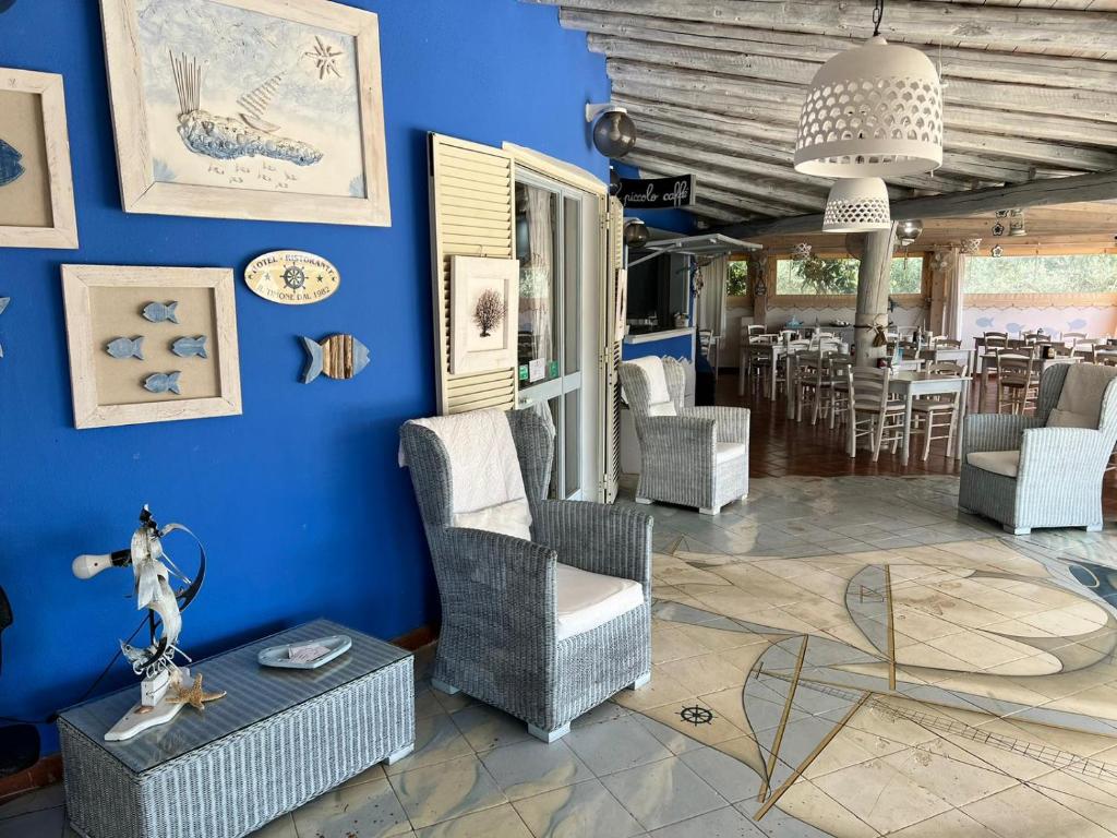 d'un salon avec des murs bleus, des chaises et une table. dans l'établissement Hotel Il Timone, à Cugnana