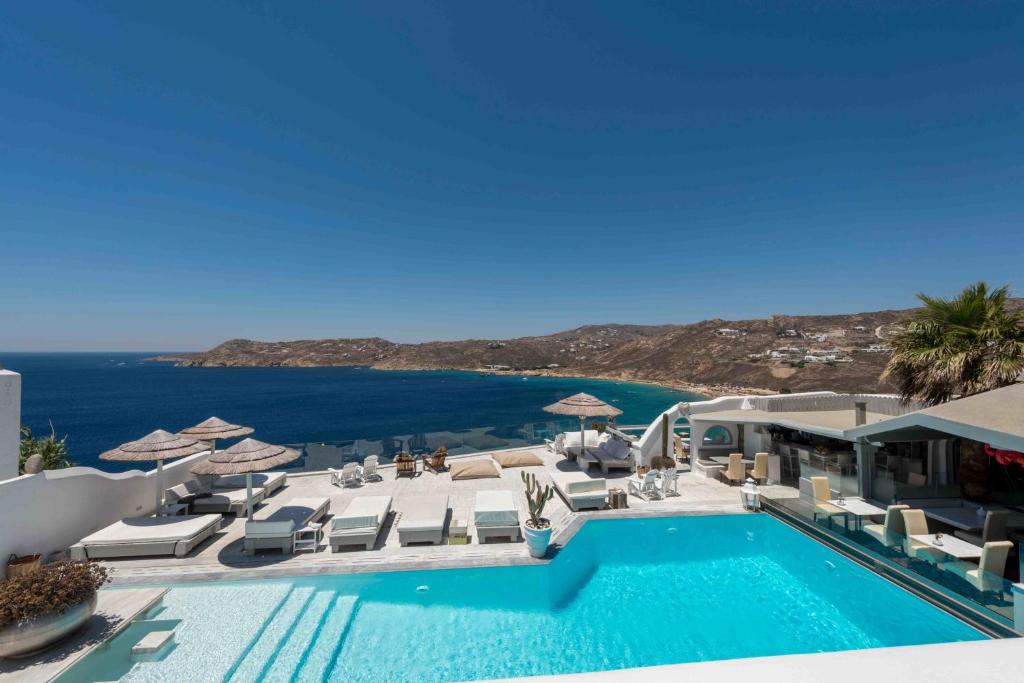 a swimming pool with chairs and a view of the ocean at Greco Philia Hotel Boutique in Elia Beach