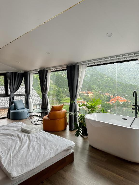 a bedroom with a tub and a large window at Bách Xanh House in Tam Ðảo