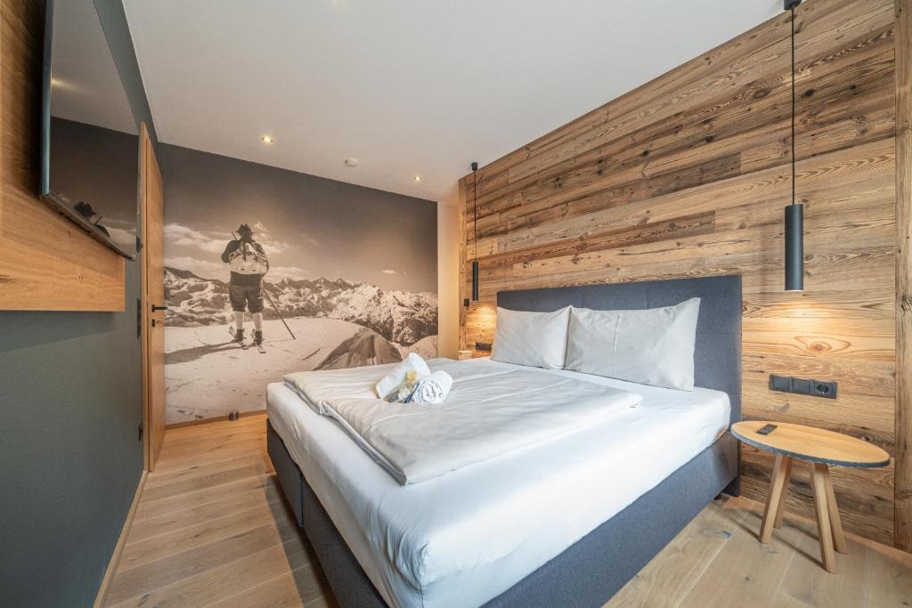 a bedroom with a large bed with a painting on the wall at Der Ortnerhof - Hotel & Reiterhof in Prägraten