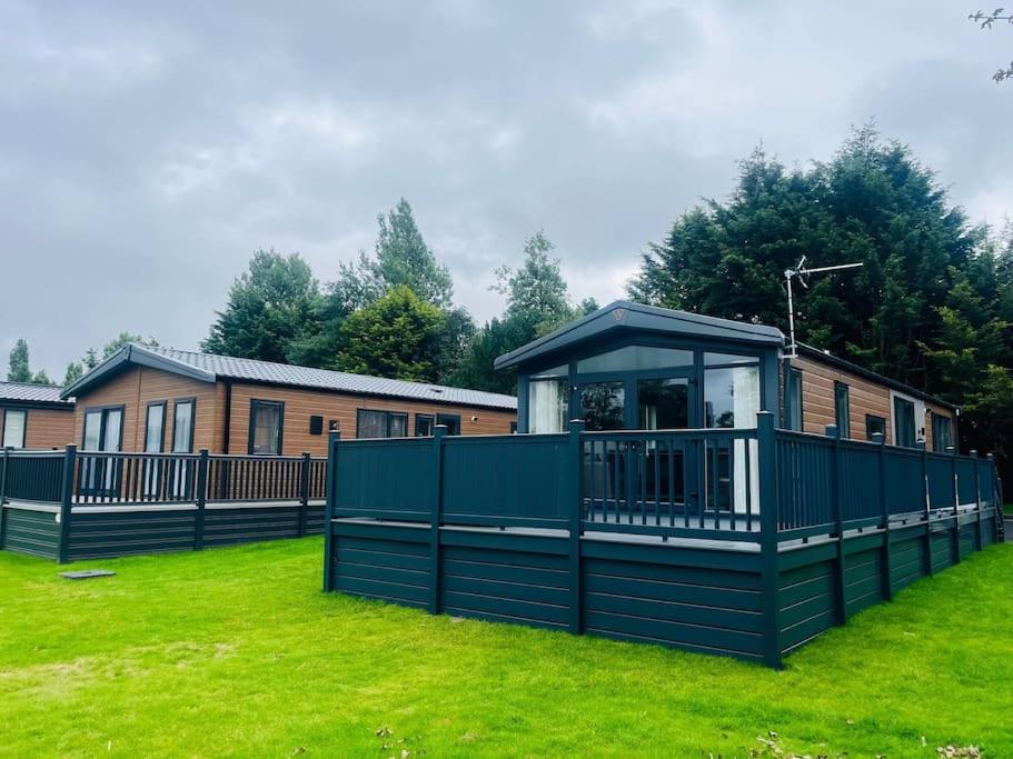 a house with a green fence in a yard at Field View Lodge with Hot Tub in York