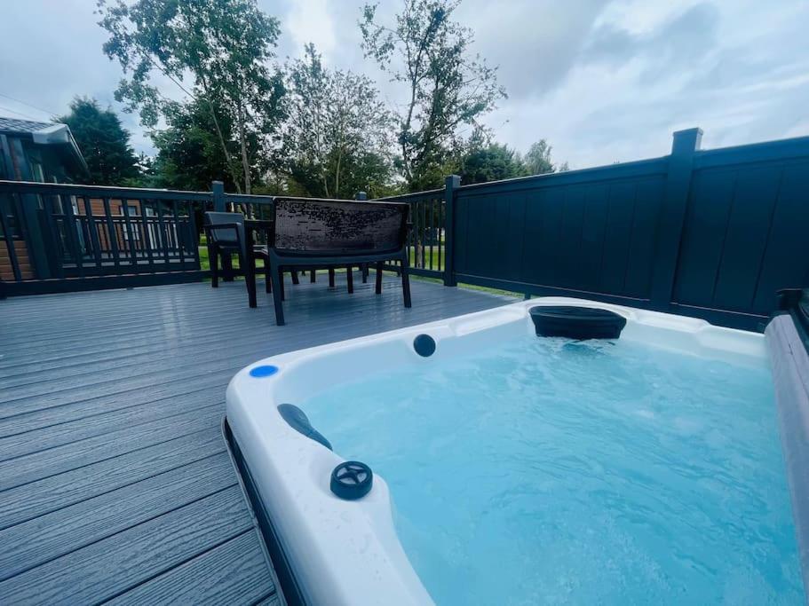 a hot tub on a deck with a table and a chair at Field View Lodge with Hot Tub in York