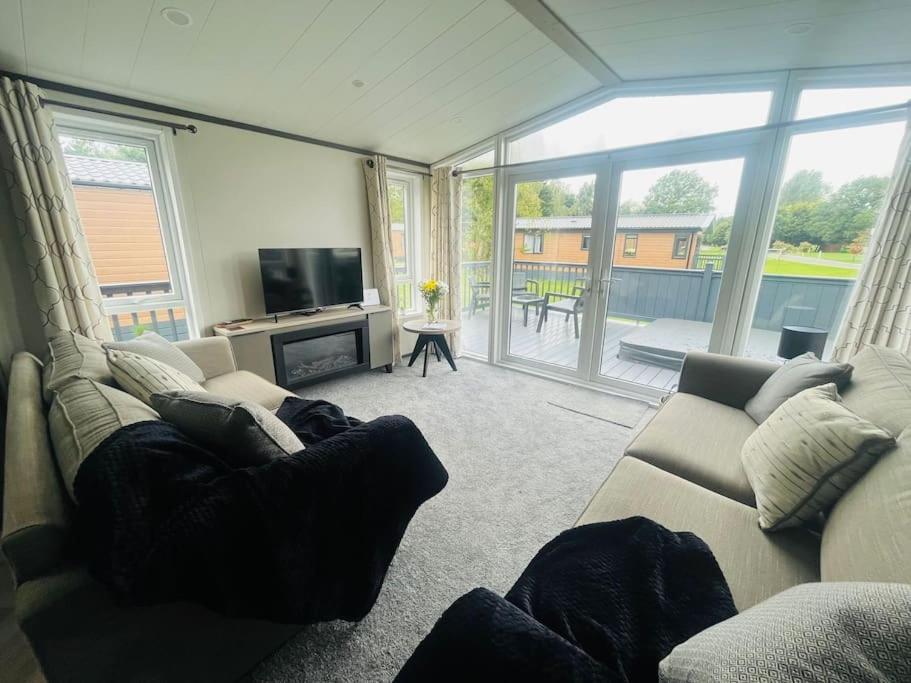 a living room with couches and a television and a balcony at Field View Lodge with Hot Tub in York