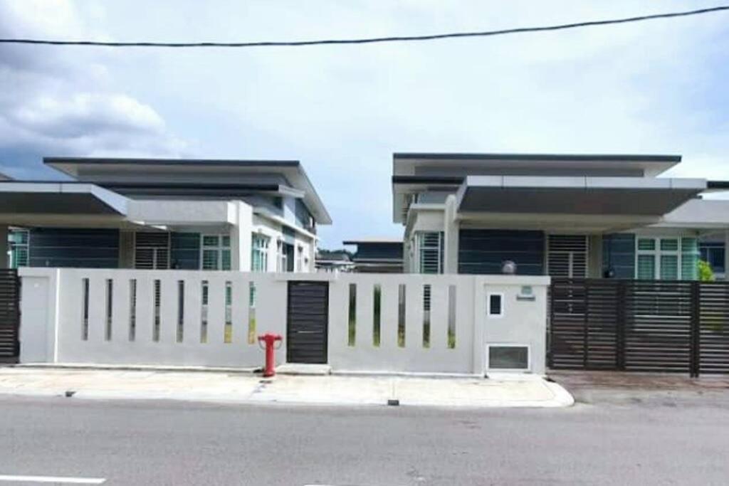 ein Haus mit einem weißen Zaun und einem roten Hydranten in der Unterkunft JOVIAL SingleStorey Bungalow 4Room10Pax `Alma in Bukit Mertajam