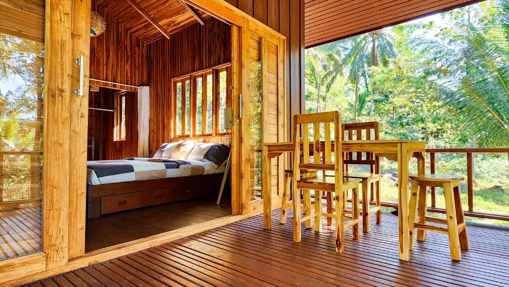 パンガン島にあるBaan Bhuwann Forest Chaletのベッドルーム1室(ベッド1台、ポーチ、テーブル、椅子付)