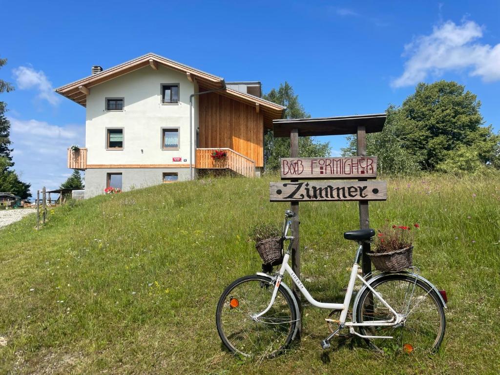 Valmorel的住宿－B&B Formighèr，停在房子前面的标志旁的自行车