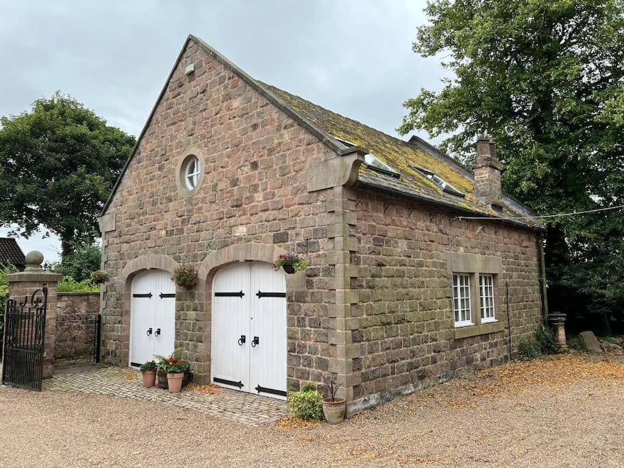 um edifício de tijolos com duas portas de garagem brancas em The Coach House Harthill em Harthill