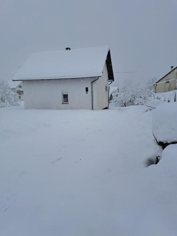 a white building in the snow with a roof at Lucija in Lovinac