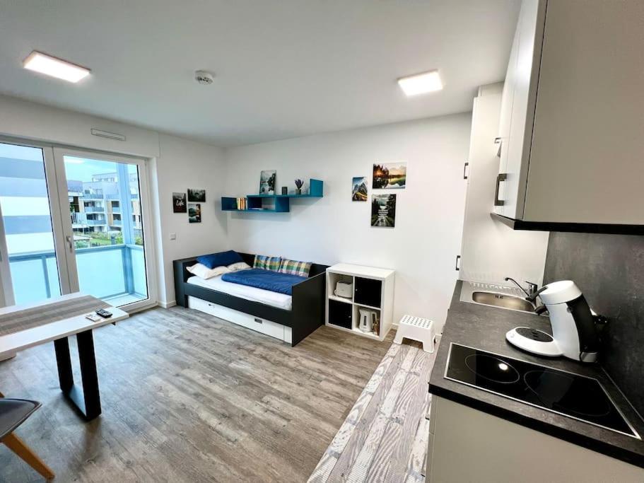 eine Küche und ein Wohnzimmer mit einem Bett in einem Zimmer in der Unterkunft Carefree Mikroapartment inkl. Balkon + Tiefgarage in Augsburg