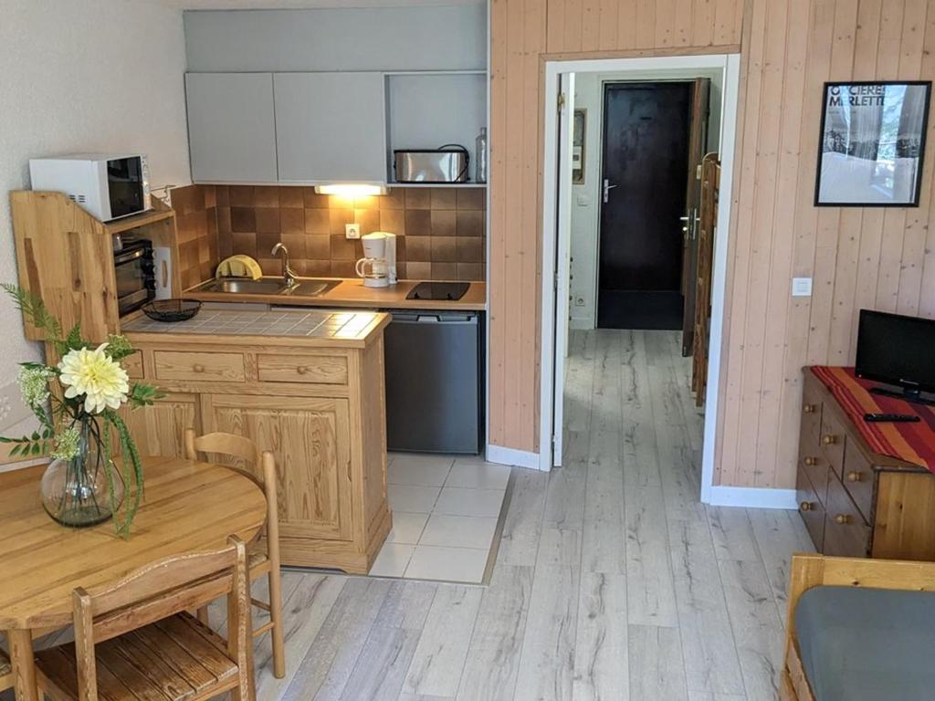 a kitchen with wooden cabinets and a table with a vase of flowers at Appartement Orcières Merlette, 1 pièce, 6 personnes - FR-1-262-98 in Forest des Baniols