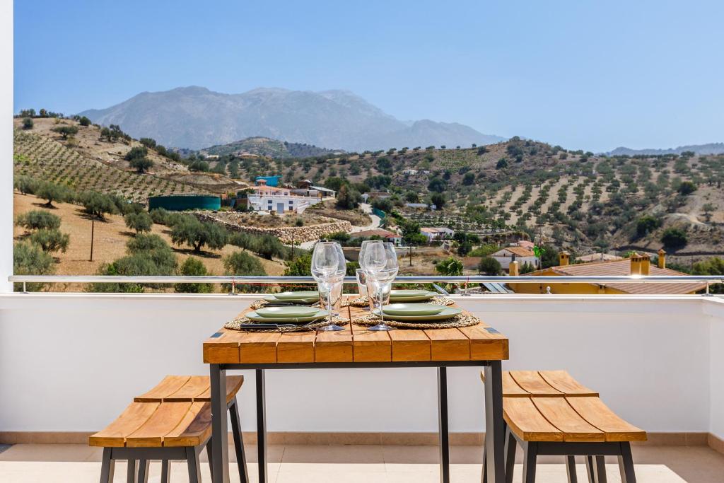 a table with wine glasses on top of a balcony at A&N La Viñuela Mountain View Duplex Large Terrace in Viñuela