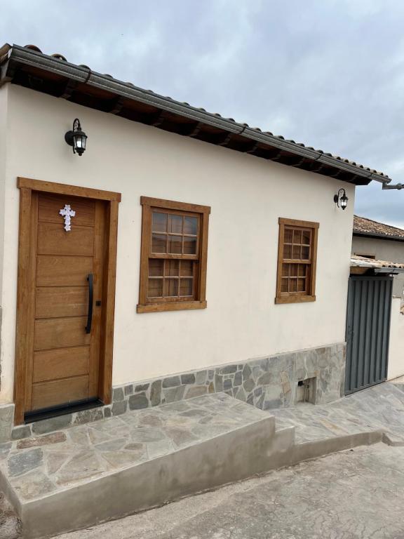 ein weißes Haus mit einer Holztür und Fenstern in der Unterkunft Casa Almeida in Tiradentes